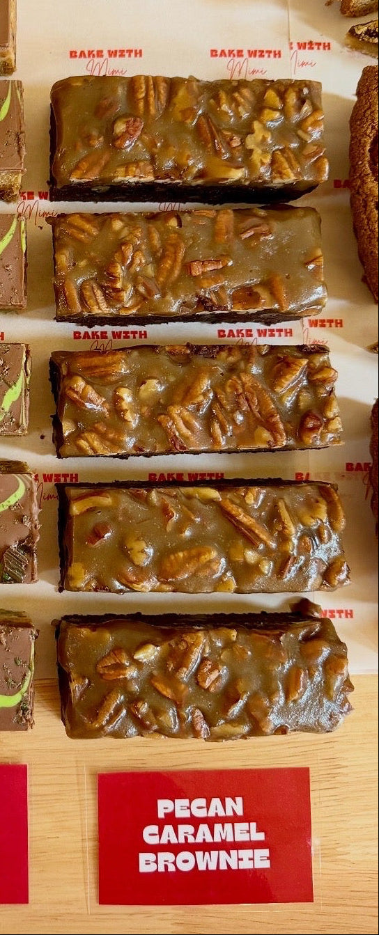 Pecan caramel brownies topped with pecans on Bake With Mimi bakery display