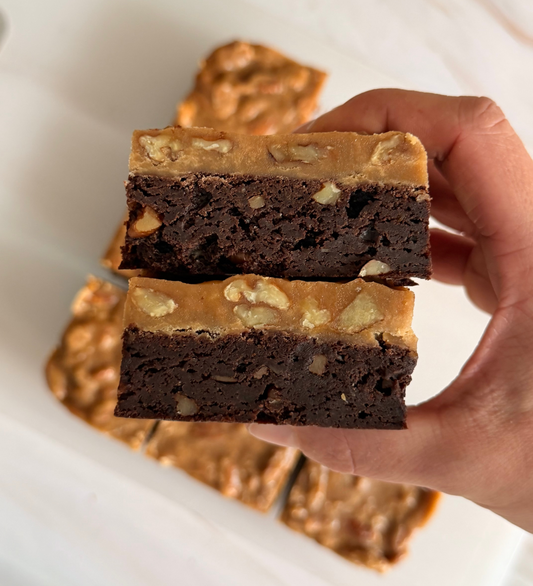 Hand holding two walnut fudge brownies stacked, Bake With Mimi gourmet treats