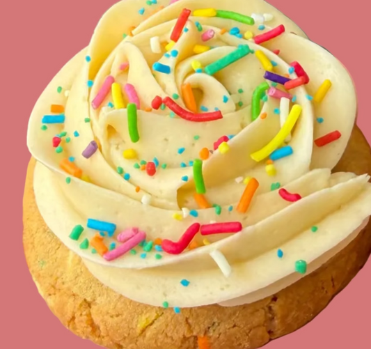 Vanilla frosted cookie with rainbow sprinkles from Bake With Mimi on pink background